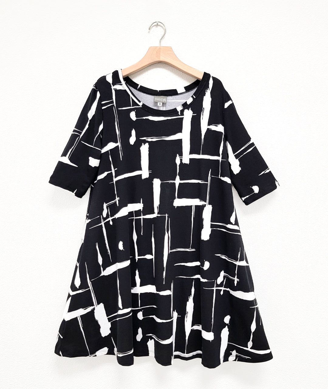 black jersey dress with a white brushstroke print. dress has 3/4 sleeves, a rounded neckline and a full swingy body