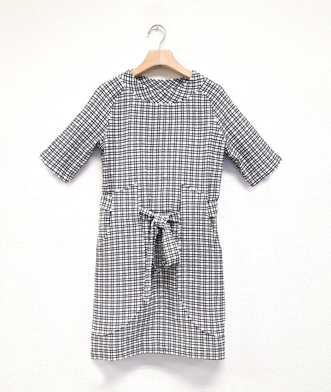 black and white check print raglan sleeve shift dress with a matching tie belt at the waist, which runs through exterior pocket loops