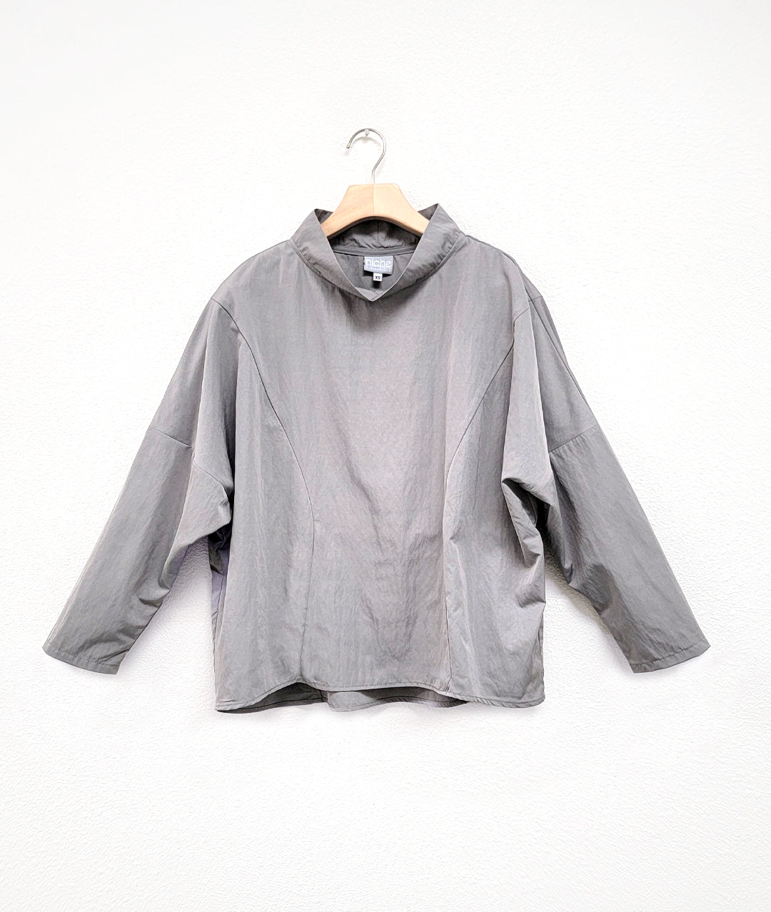 light gray pullover top with dropped shoulders, princess seams and a standing cowl neckline