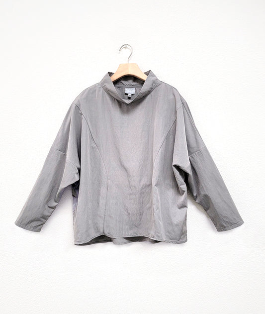 light gray pullover top with dropped shoulders, princess seams and a standing cowl neckline