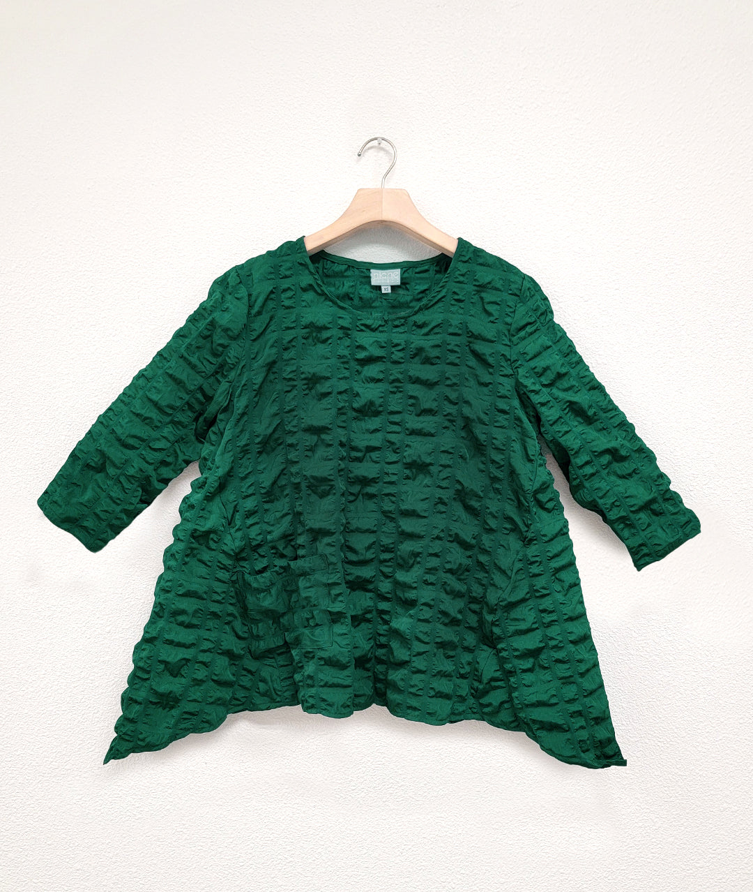 emerald green pullover top with 3/4 sleeves and a dipped hem at each side