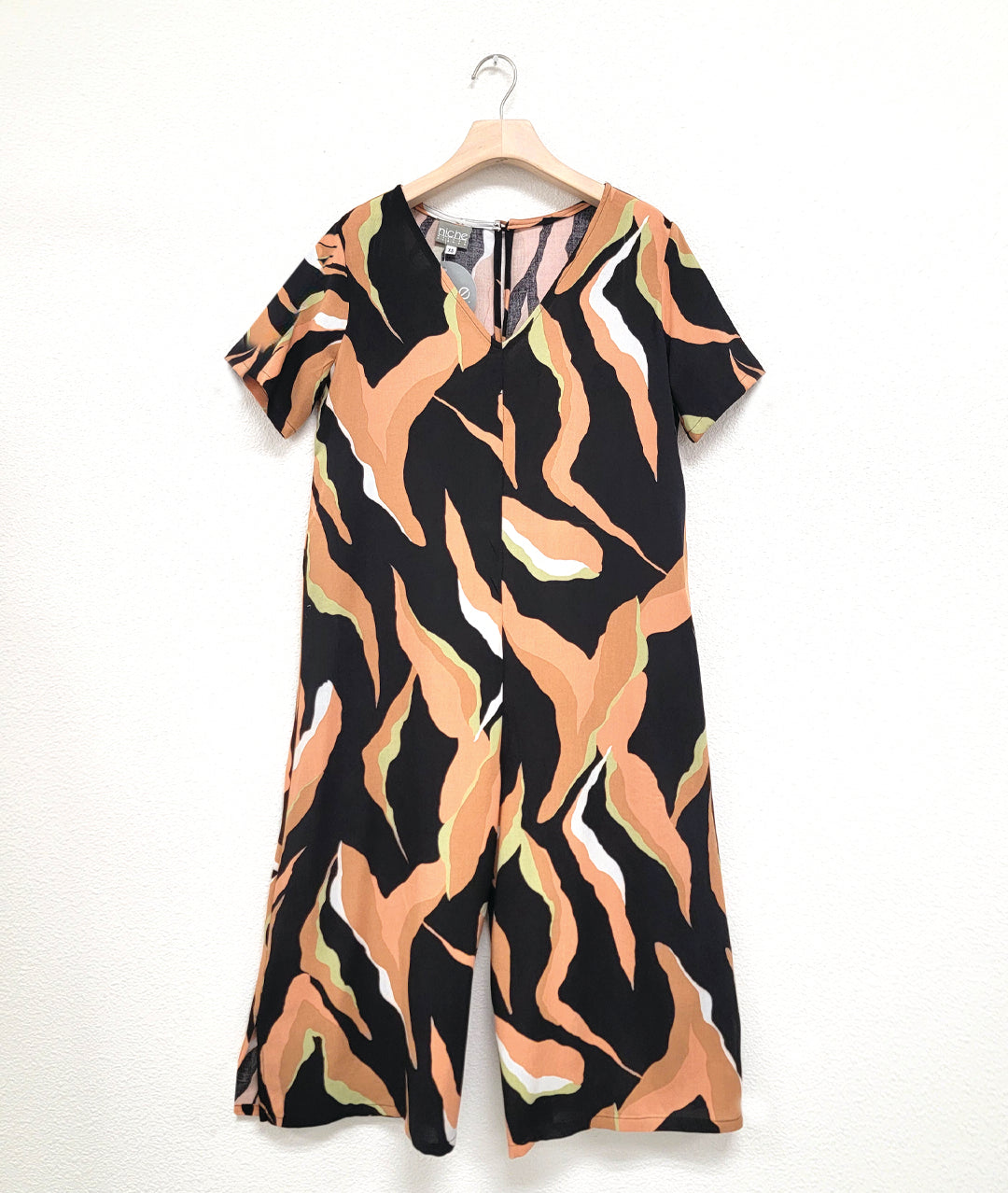 wide, cropped leg jumpsuit with a loose fitting body, short sleeves and a vneck. jumpsuit is black with a multi color orange tone tiger stripe