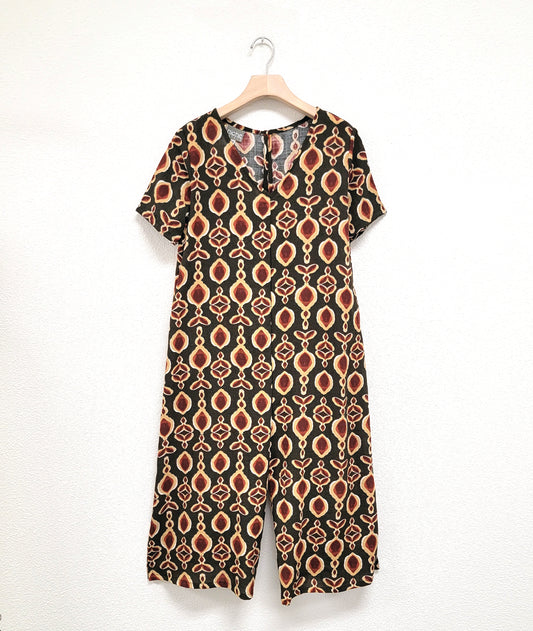 wide, cropped leg jumpsuit with a loose fitting body, short sleeves and a vneck. jumpsuit is olive with a multi color ink print