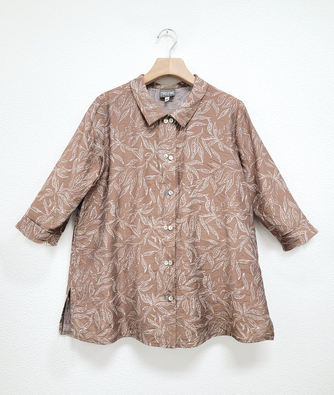 taupe button down blouse with a white leaf print and twinbutton detail, 3/4 sleeves and a long body