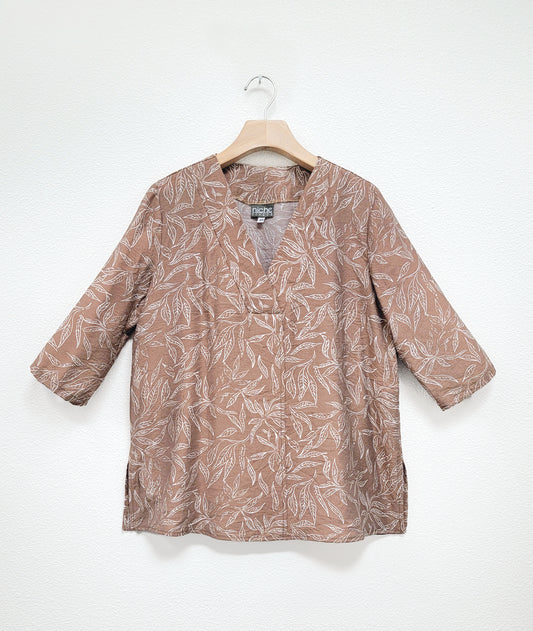 taupe leaf print  top with a white leaf print. top has a vneck and 3/4 sleeves and a center front seam and splits on either side.