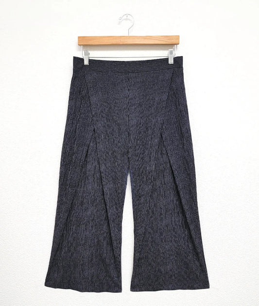 Grey pleated pants on a hanger against a white background