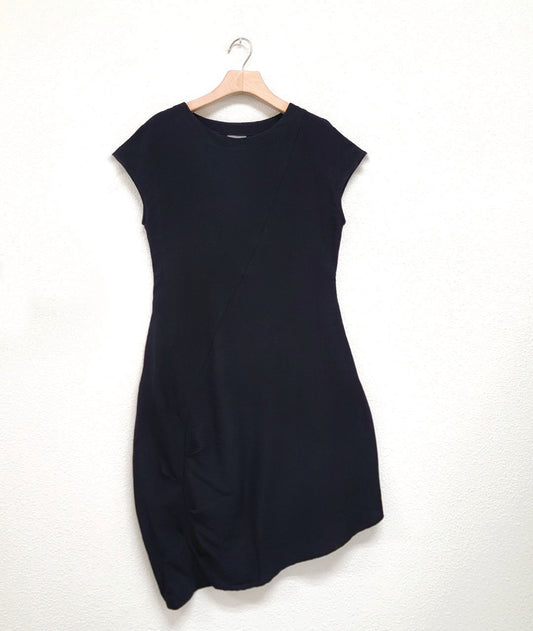 black shift dress with a capped sleeve and an asymmetrical single seam across the body with a pleated detail along the lower half