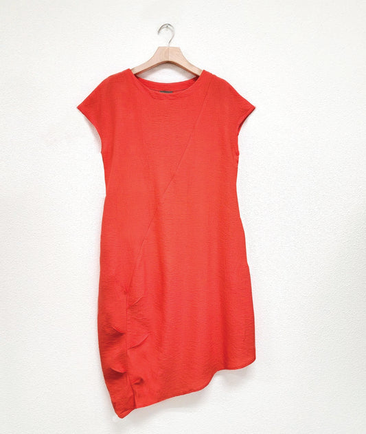 coral color shift dress with a capped sleeve and an asymmetrical single seam across the body with a pleated detail along the lower half