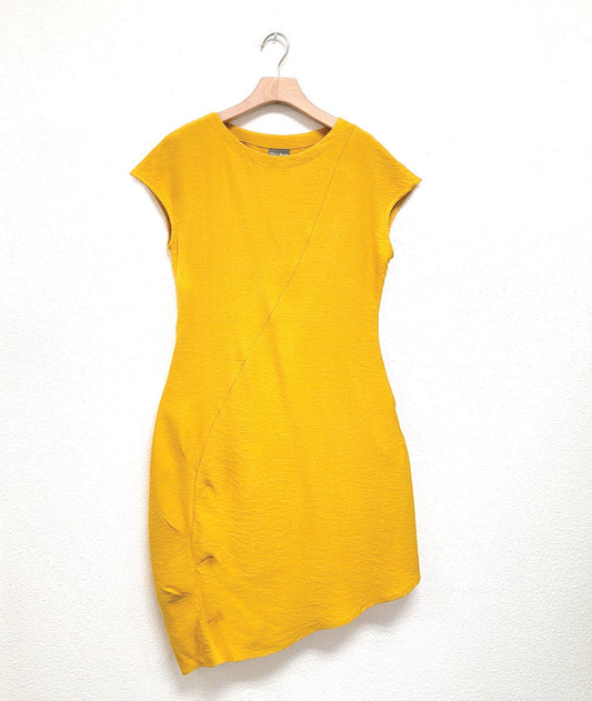 yellow shift dress with a capped sleeve and an asymmetrical single seam across the body with a pleated detail along the lower half