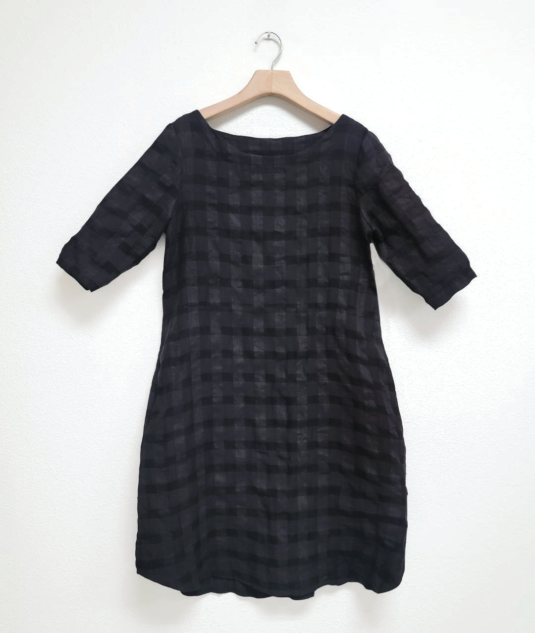 oversized black shift dress with a round neckline, 3/4 sleeves, a curved hem and a large check print weave giving the fabric differing shades of grey and black