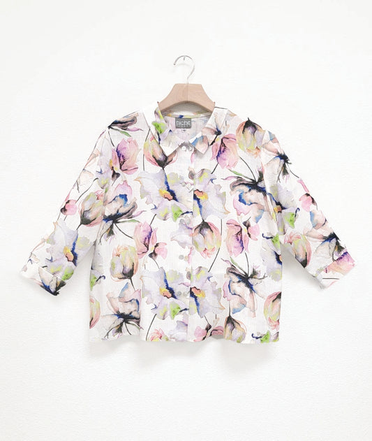 white button down blouse with a multicolor floral print. blouse has a cropped, boxy body, 3/4 sleeves and a twinbutton detail