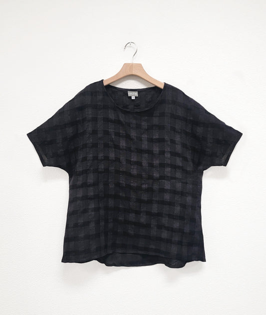 black  pullover top with a large rounded neckline, elbow length raglan sleeve, and a large checkered print woven into the fabric