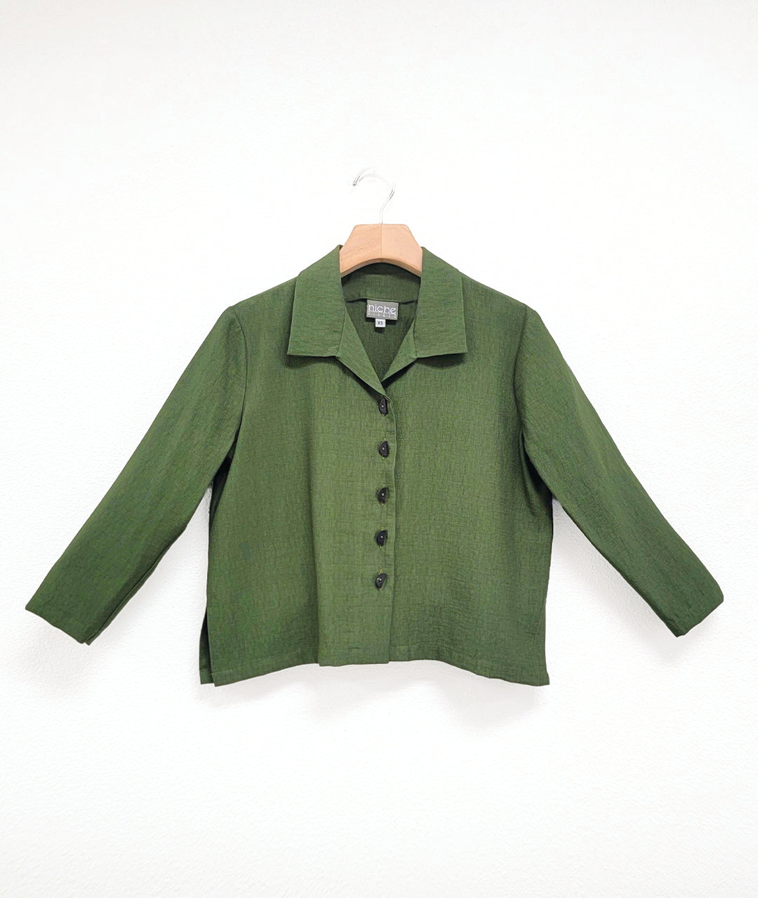 pine green button down blouse with a short boxy body and 3/4 sleeves. small splits at either hip seam