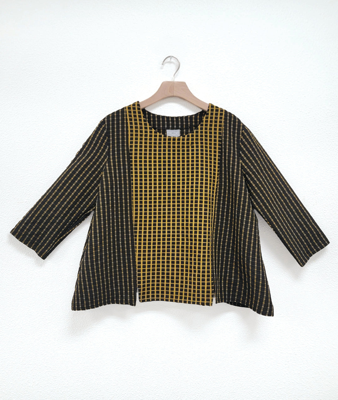 pullover black top with a yellow grid print, 3/4 sleeves, and contrasting center panels in the front and back. contrast is a reverse of the rest of the fabric