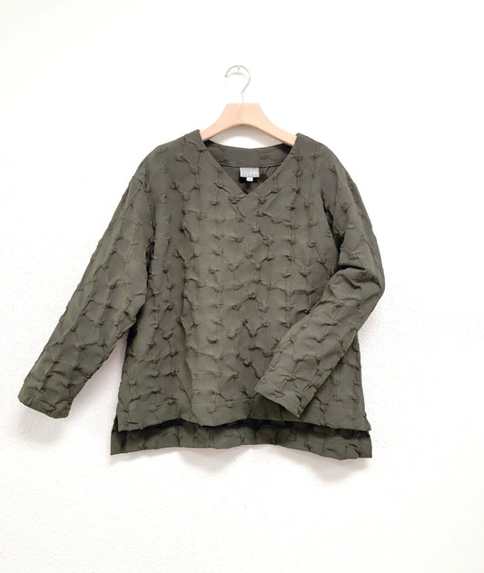 army green pullover blouse with a puckered dot texture. top has long sleeves, a v-neck and a stairstep hem