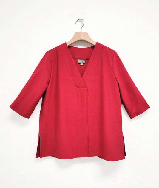 Red half sleeve top with v-neck on a hanger against a white background