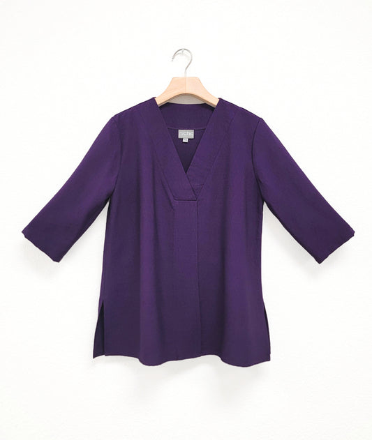 Purple half sleeve top with v-neck on a hanger against a white background