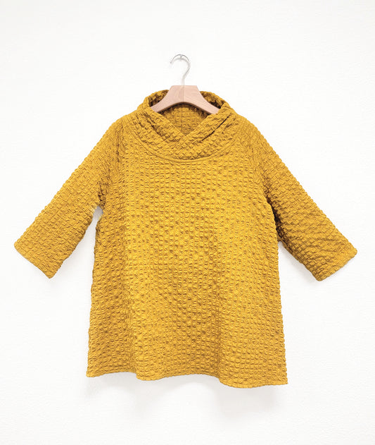 mustard yellow textured half sleeve shirt on a hanger against a white background
