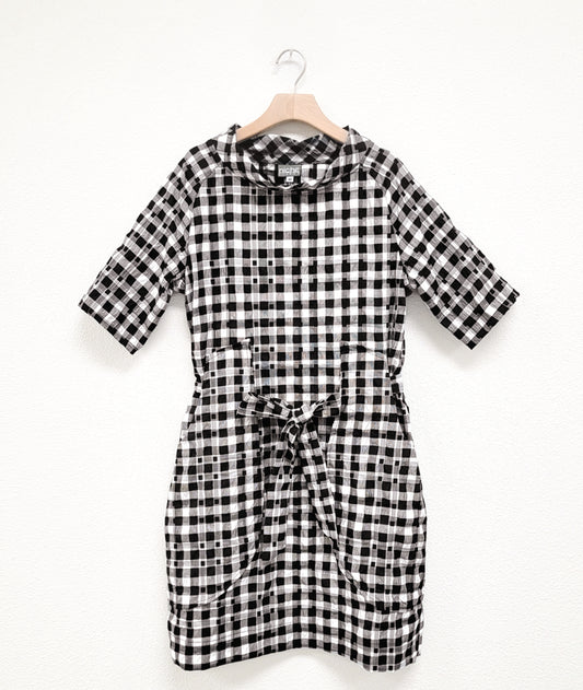 black and white plaid raglan sleeve shift dress with a matching tie belt at the waist, which runs through exterior pocket loops