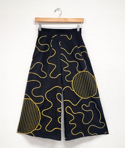 wide leg black pant with a yellow swirl embroidery and grid print round patches