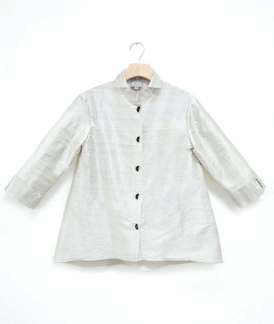 white dupioni silk blouse with black half-moon buttons, a wide cuff on a 3/4 sleeve, and a double collar. blouse has a lower hem in the back.