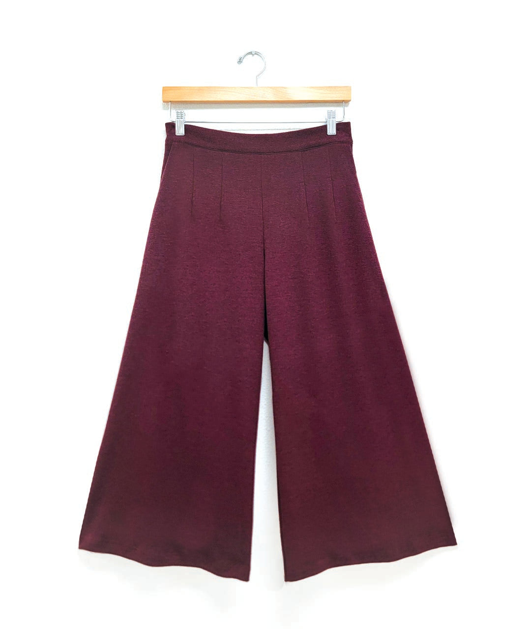 Purple wide-leg pants on a hanger against a white background