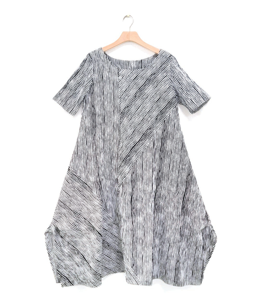 black and white striped dress with contrasting panels of directional stripes. Dress has a round neckline, elbow length sleeves and splits and tucks at the sides