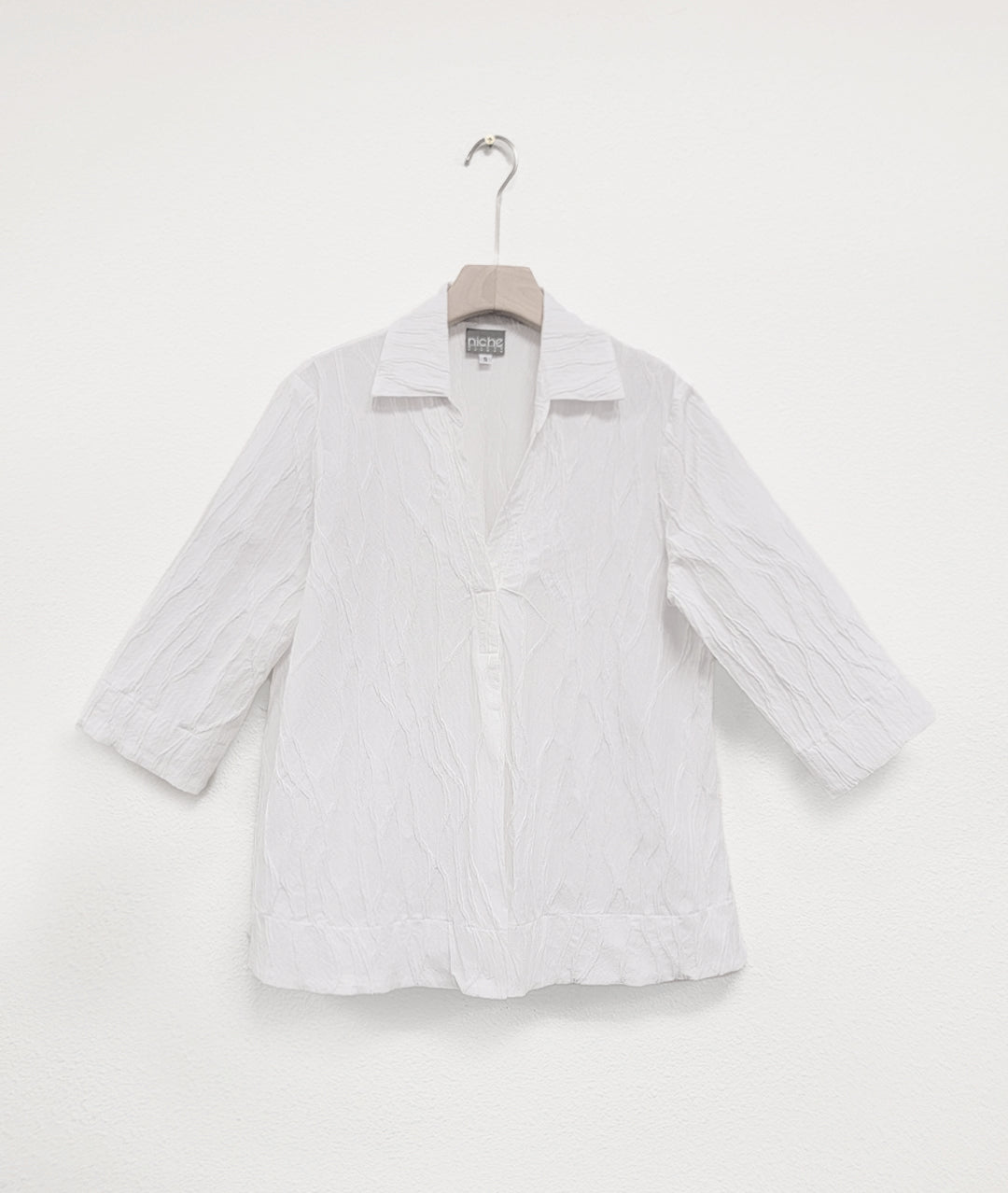 pullover white top with 3/4 sleeves, a deep v neckline and a crinkled line texture