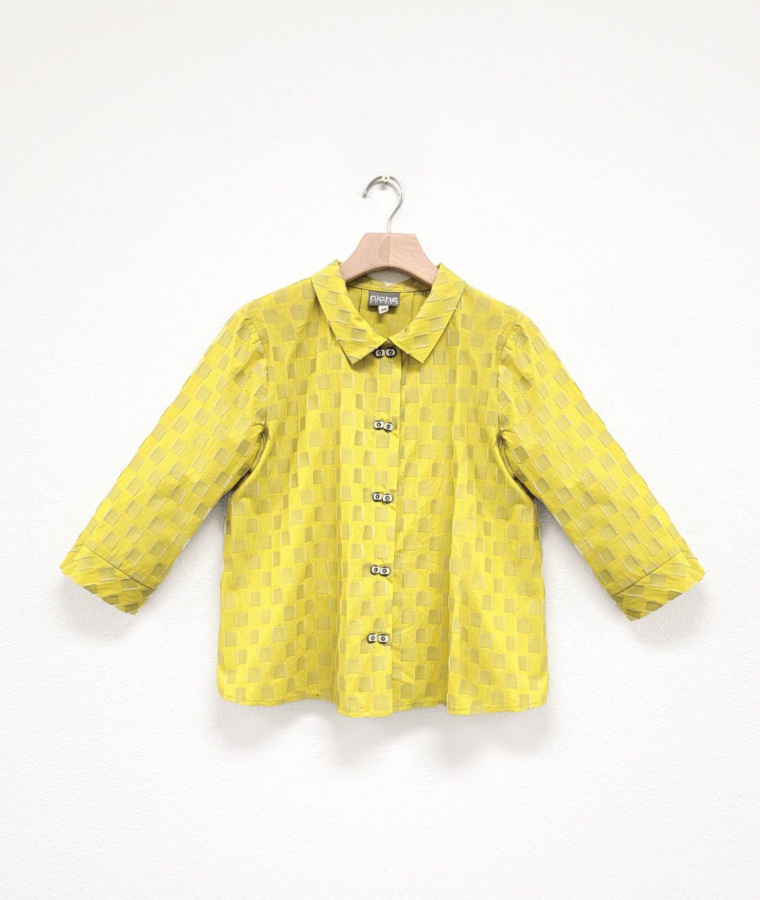 Yellow checkered button up shirt on a white background