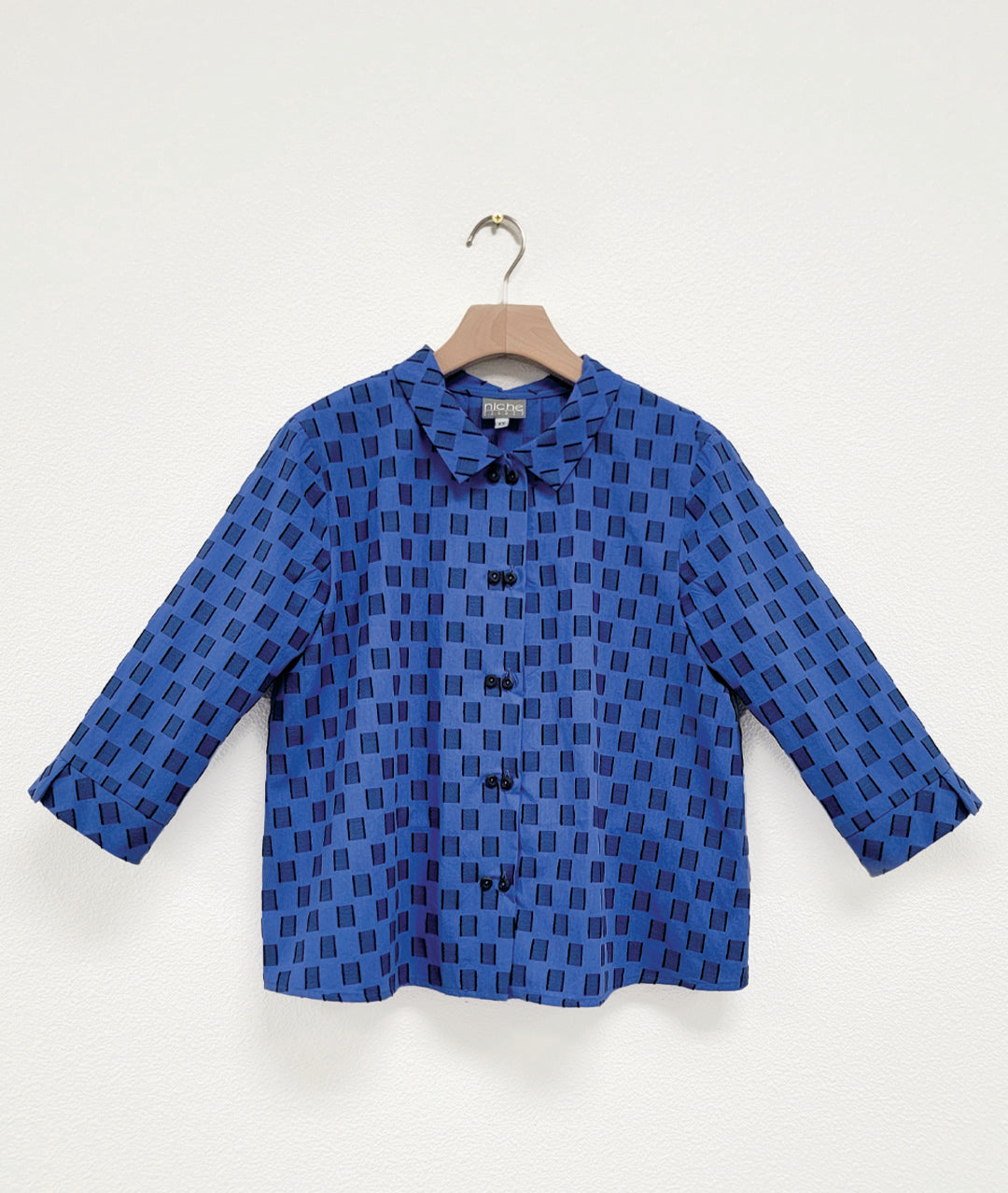Blue checkered button up shirt on a hanger against a white background
