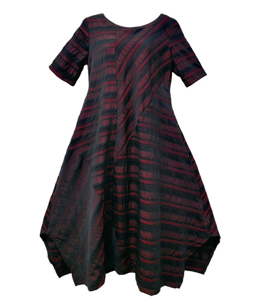 black and deep red striped dress with contrasting panels of directional stripes. Dress has a round neckline, elbow length sleeves and splits and tucks at the sides