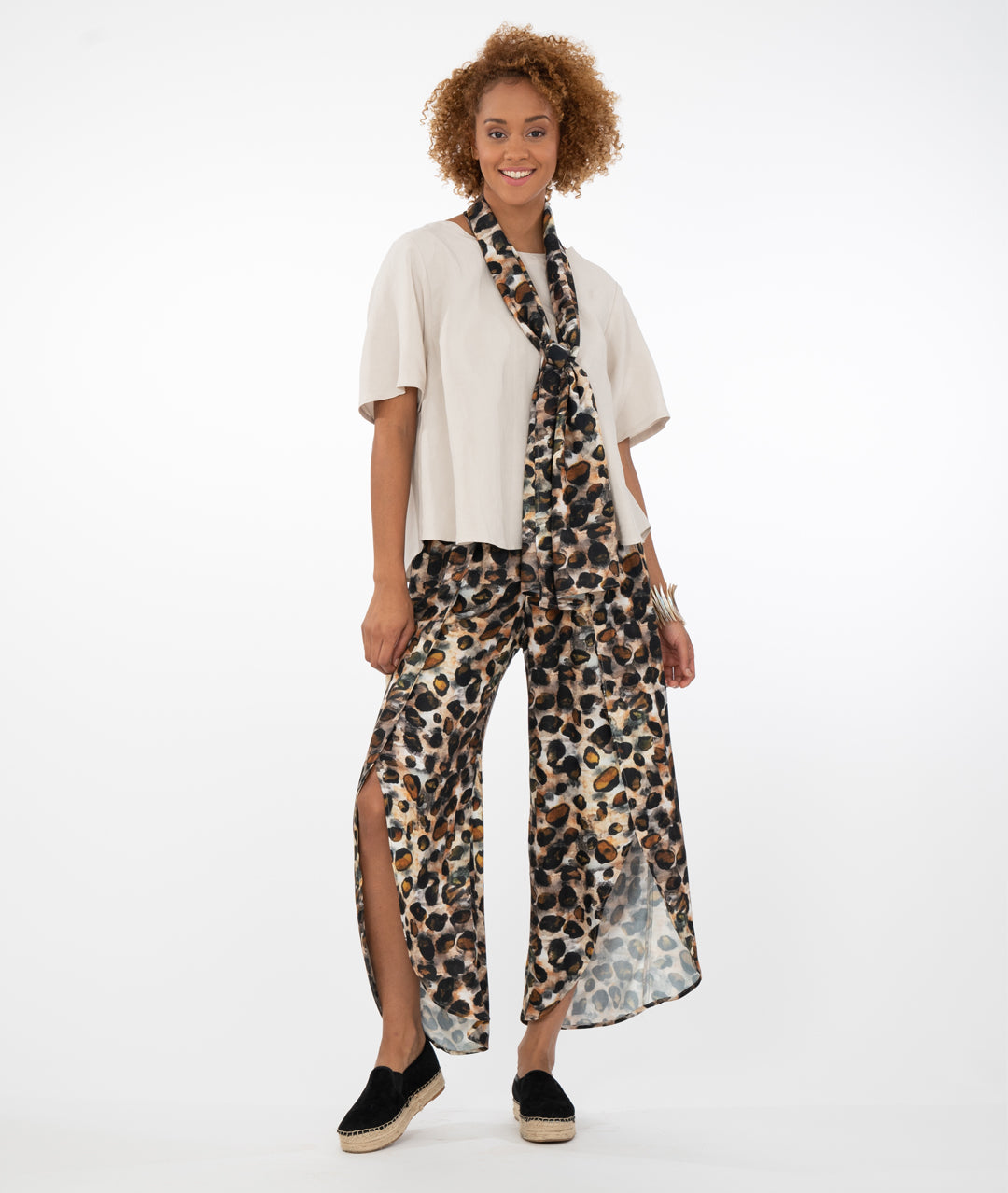 model in a bone colored top with animal print pants and scarf, in front of a white background