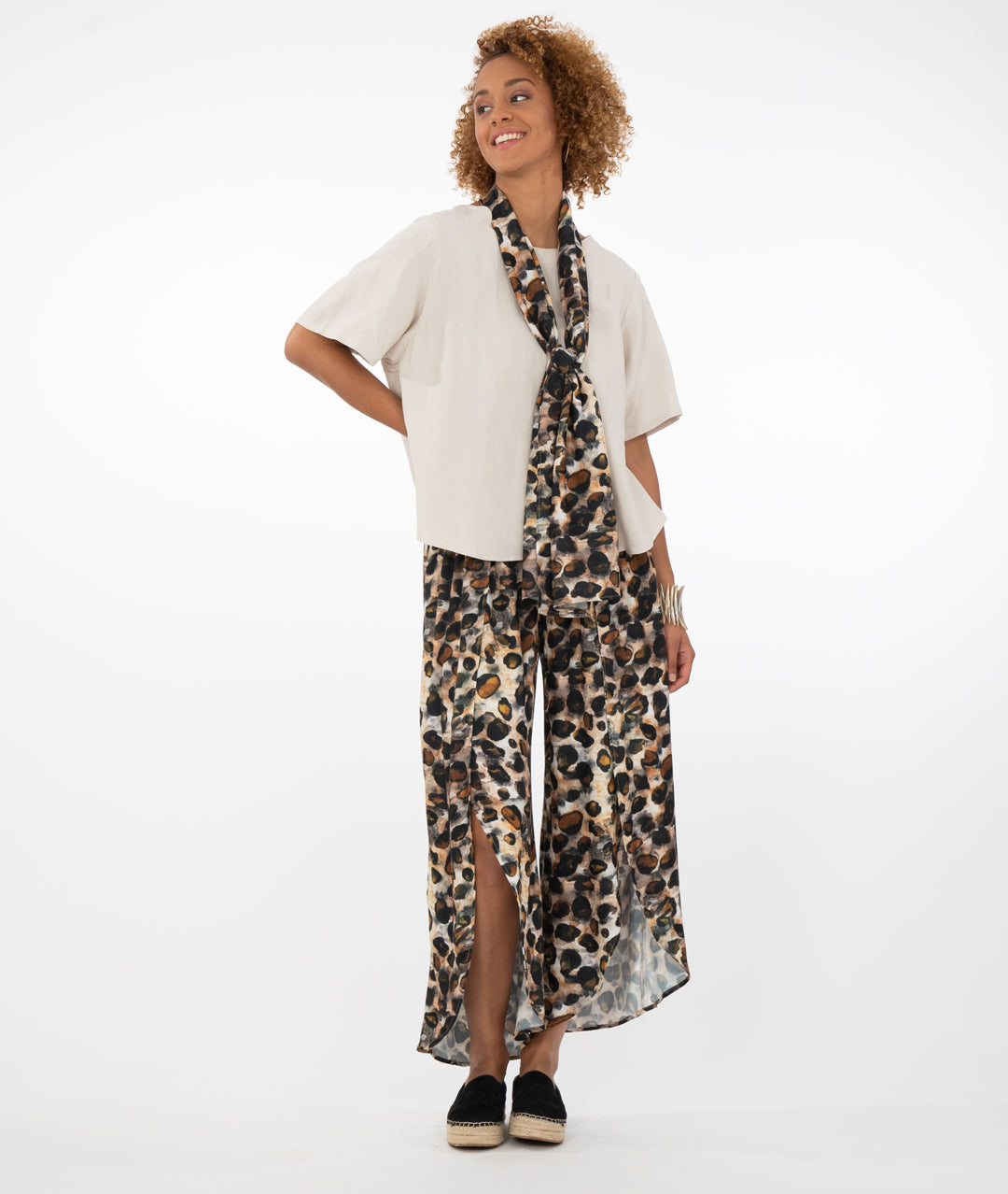 model in a bone colored top with animal print pants and scarf, in front of a white background