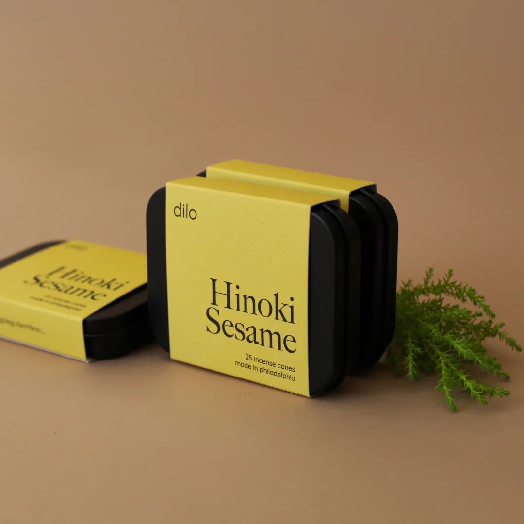 three hinoki sesame scented incense cone packaging with piece of greenery