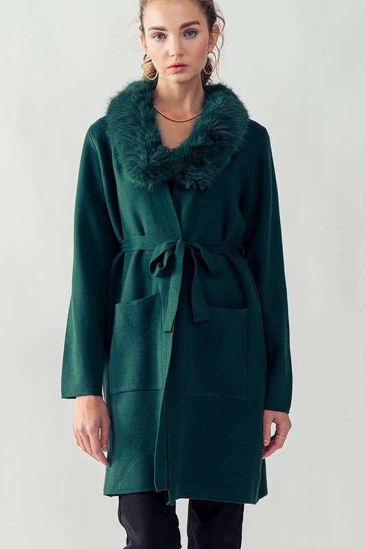 model wearing hunter green cover up featuring two front pockets, tie belt and fur collar