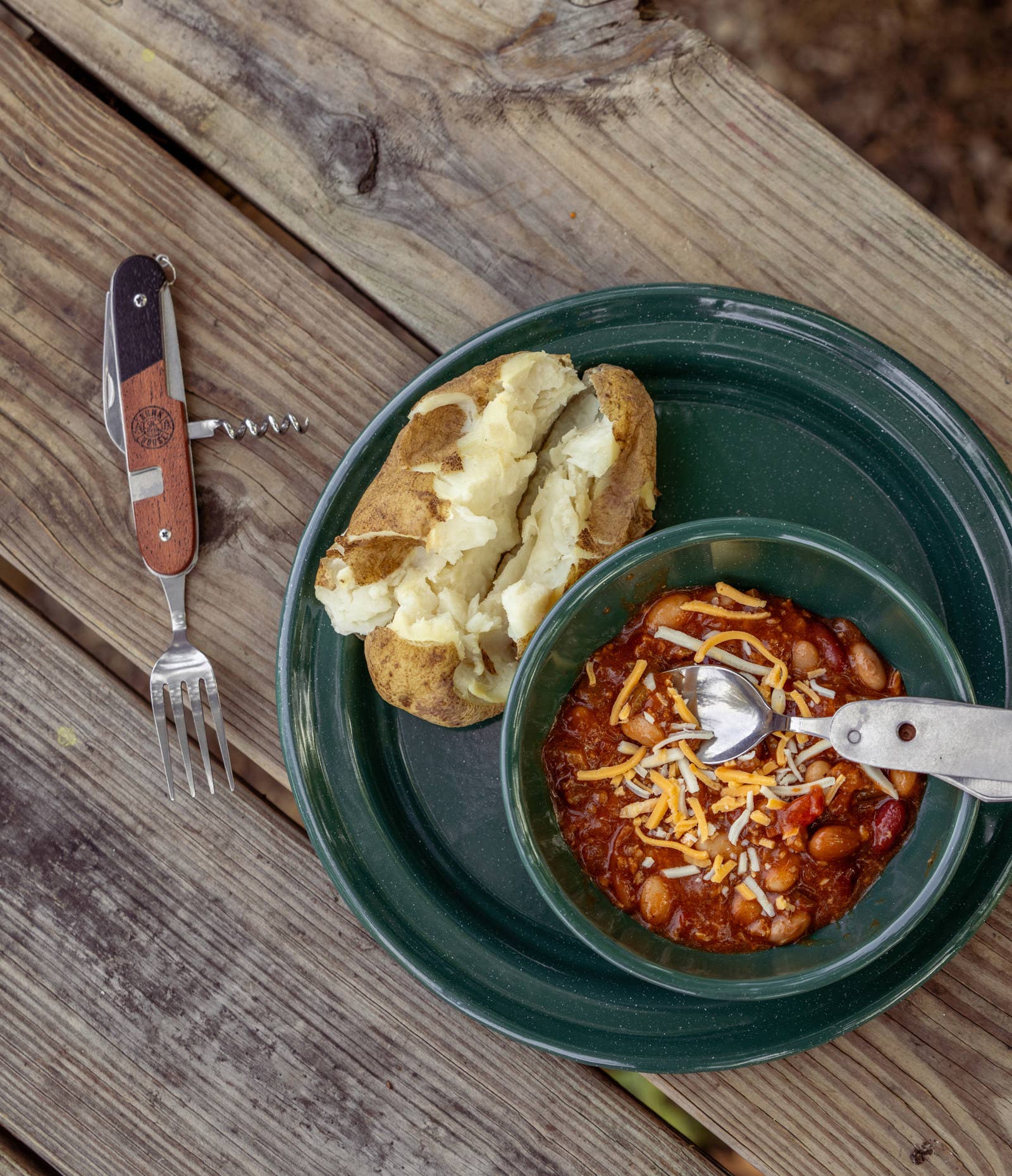 plate with soup, baked potato and tool featuring fork and wine opener