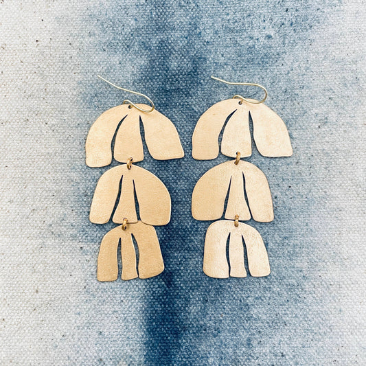 Pair of gold layered earrings on a textured blue surface