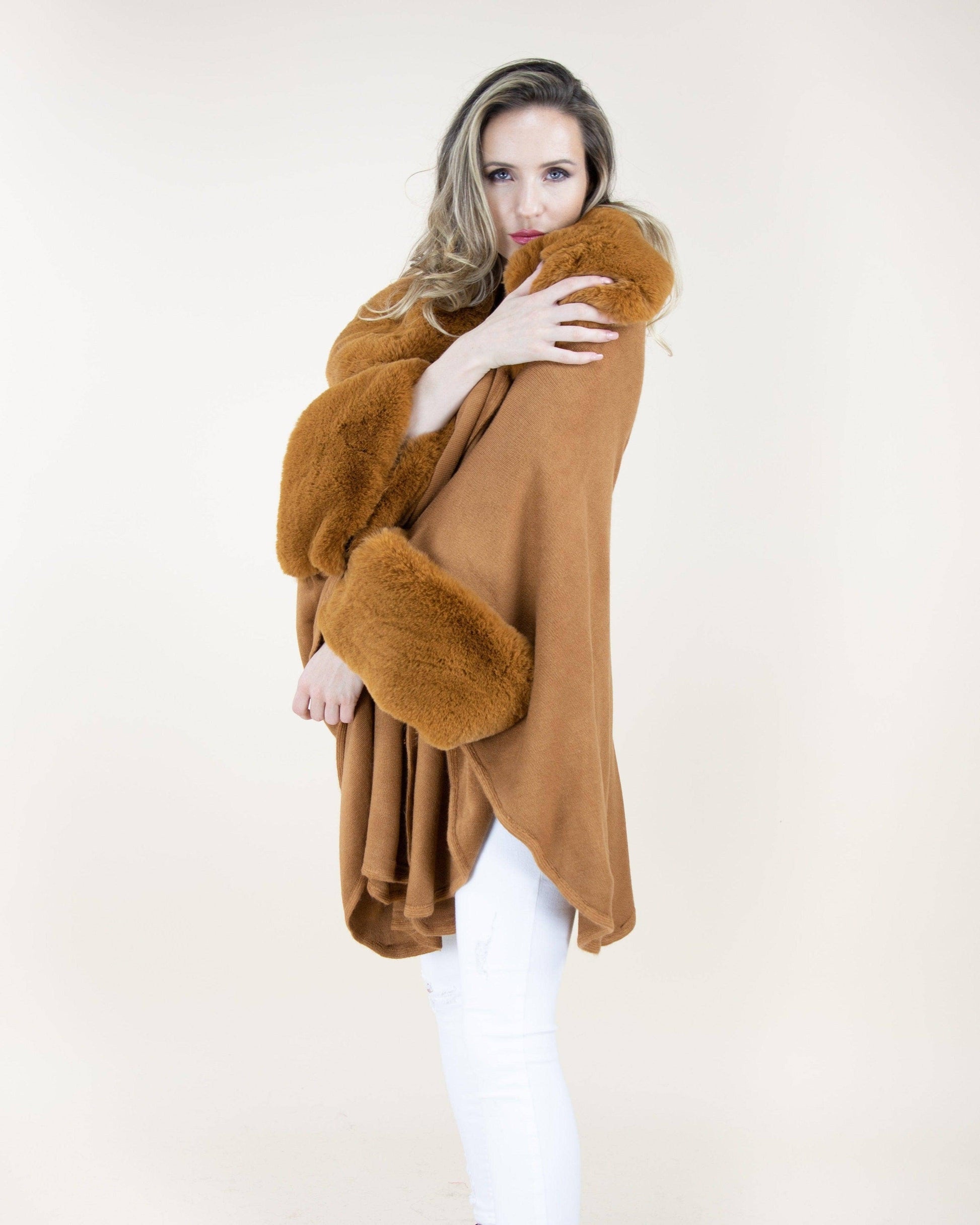 Woman wearing a brown fur-trimmed poncho against a white background