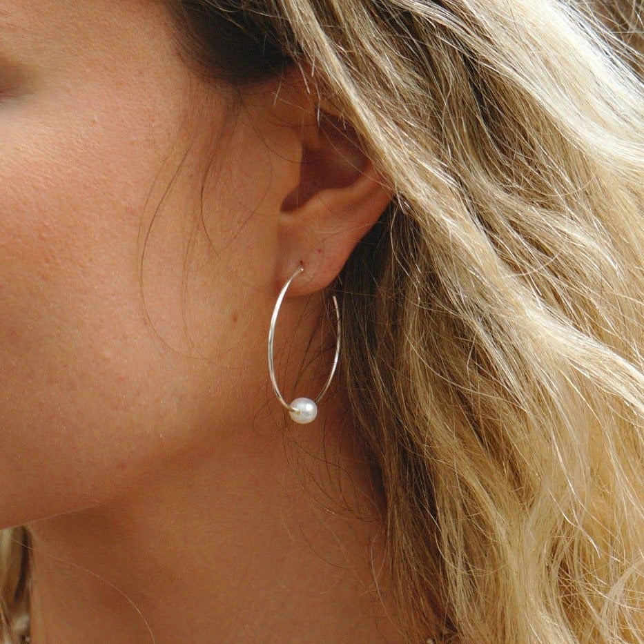 Close-up of a woman wearing pearl earrings and necklaces.