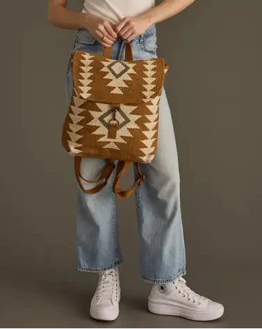Person holding a brown and beige patterned backpack against a plain background