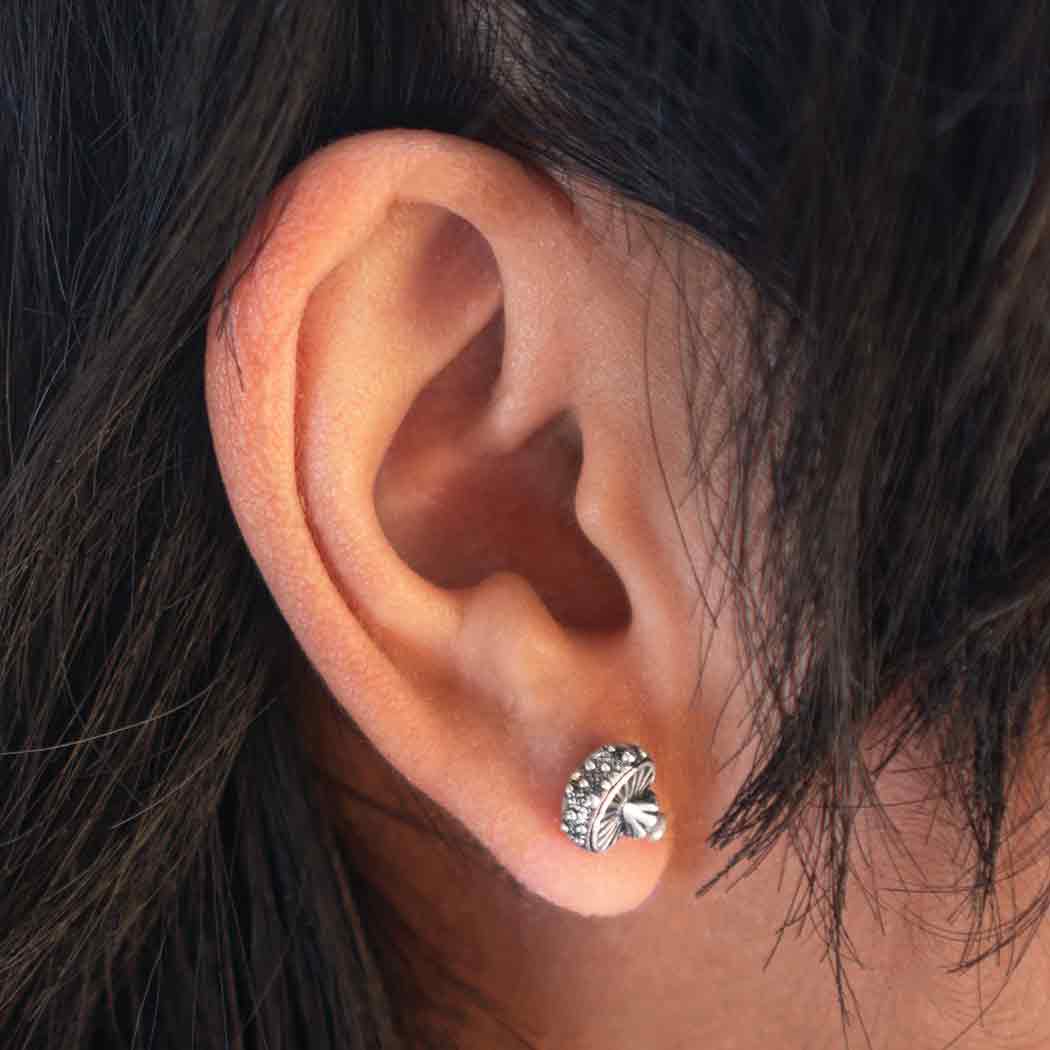 Close-up of an ear wearing a silver earring with dark hair.