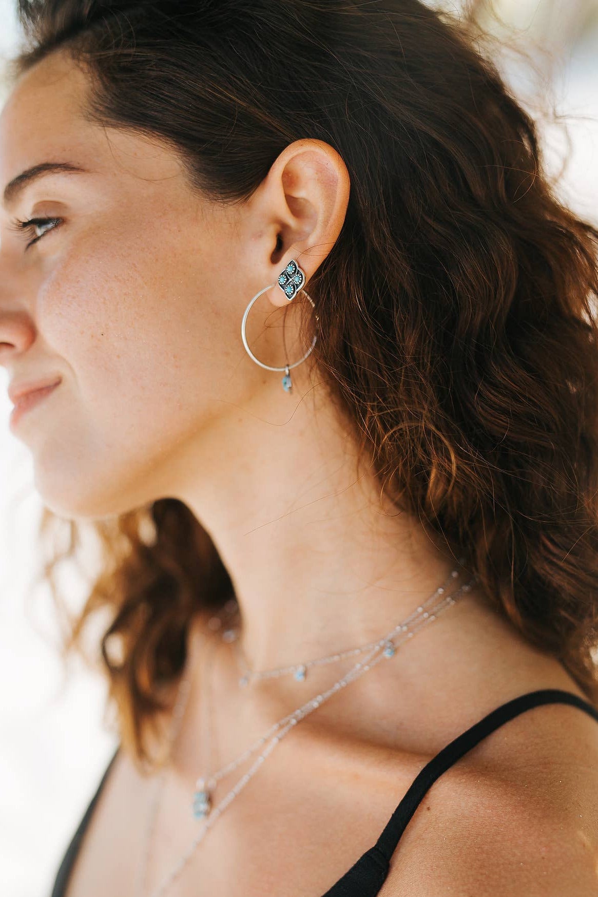 Woman wearing hoop earrings and a necklace with a blurred background