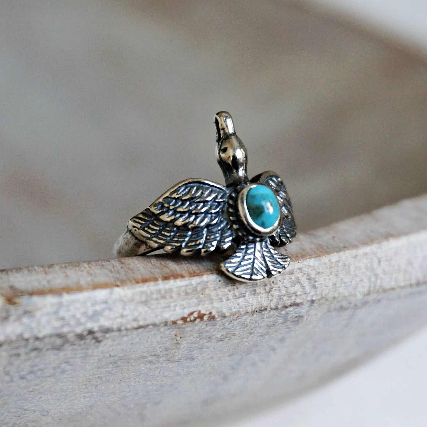 Silver turtle pendant with turquoise stone on a wooden surface