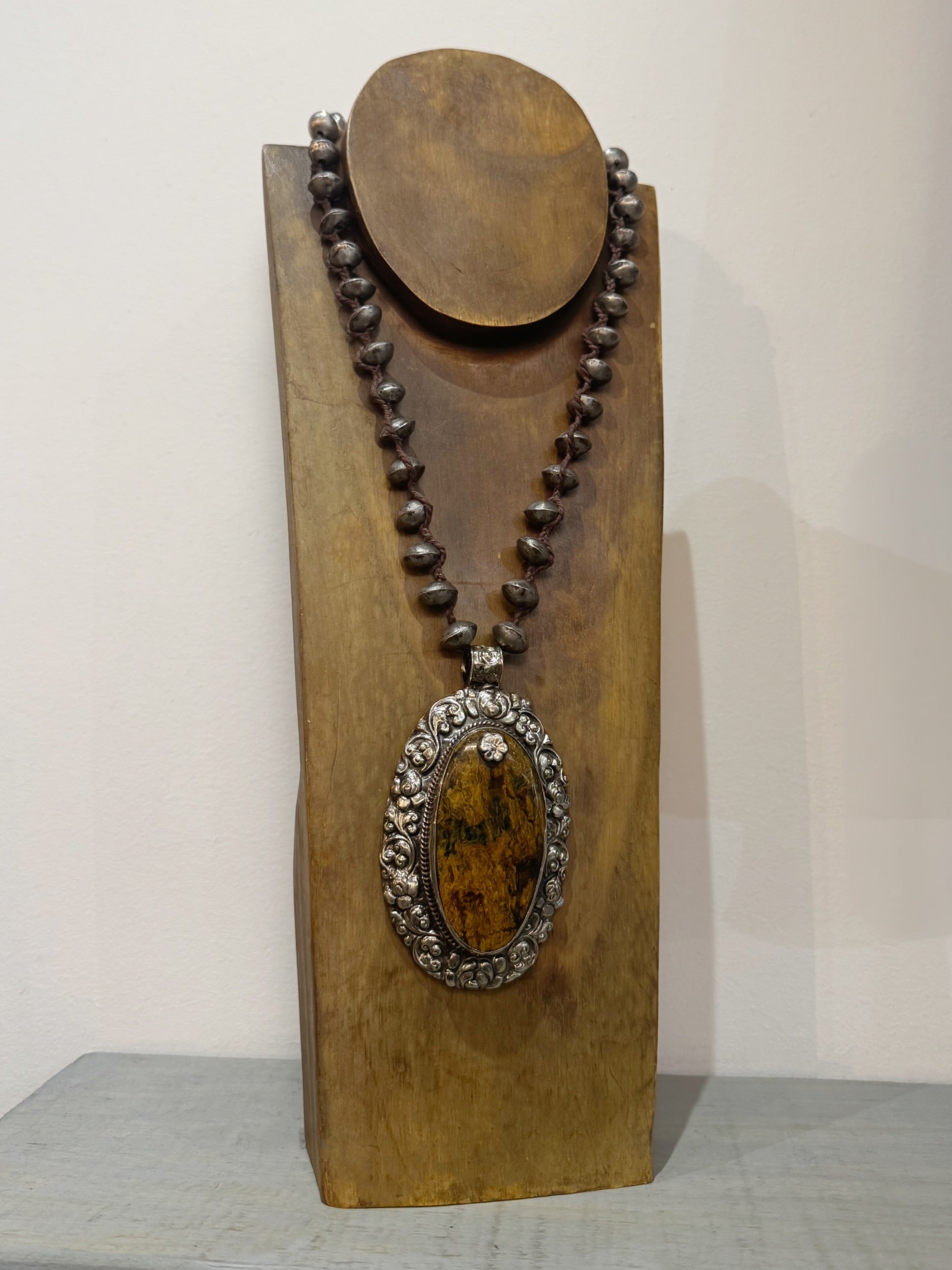 Necklace with a pendant on a wooden stand against a plain background