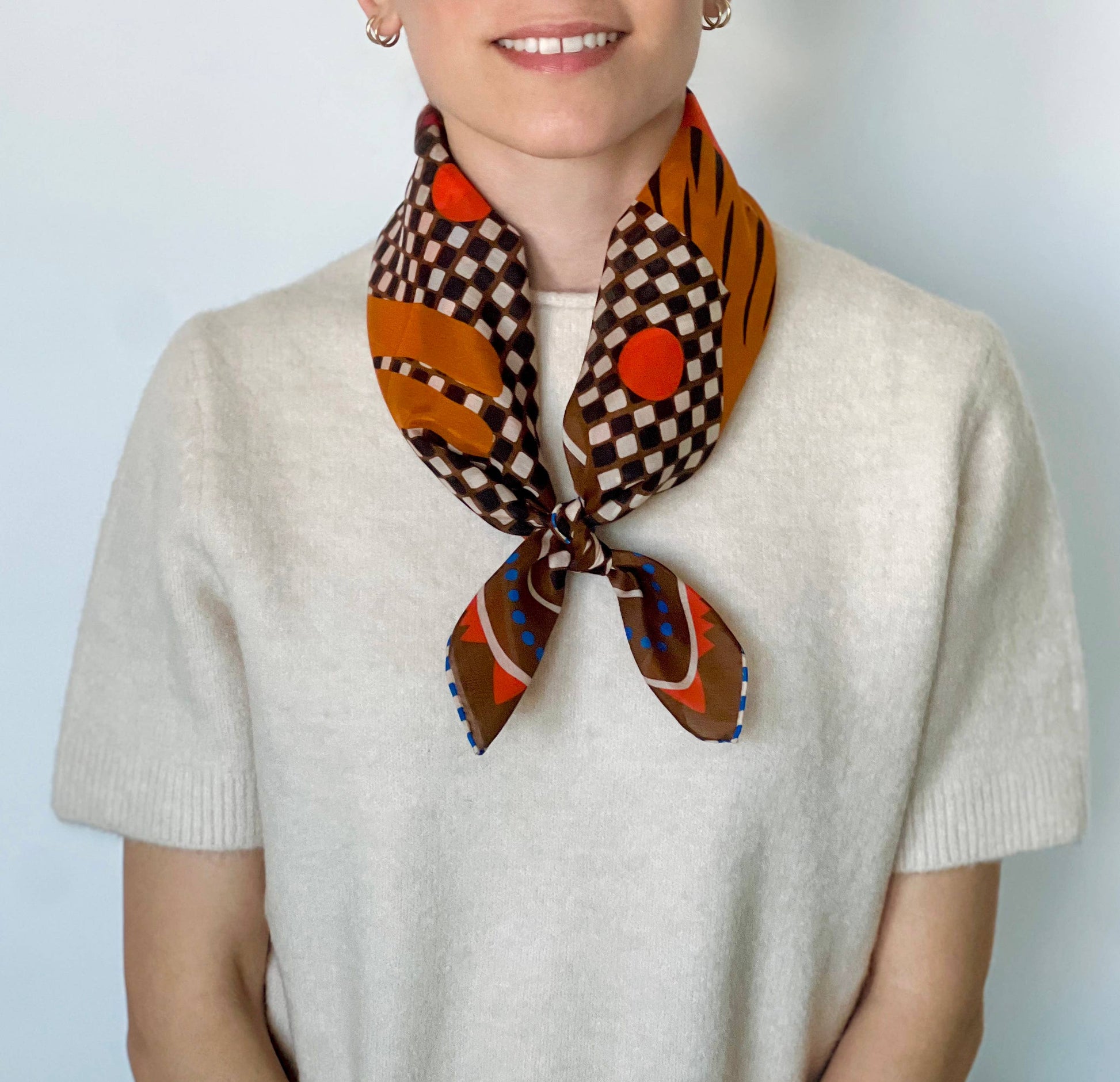 model wearing bandana tied around neck with beige top and white background