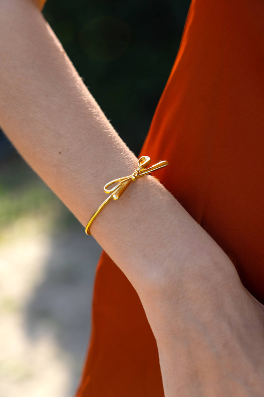 close up of gold bow cuff bracelet on model’s wrist 