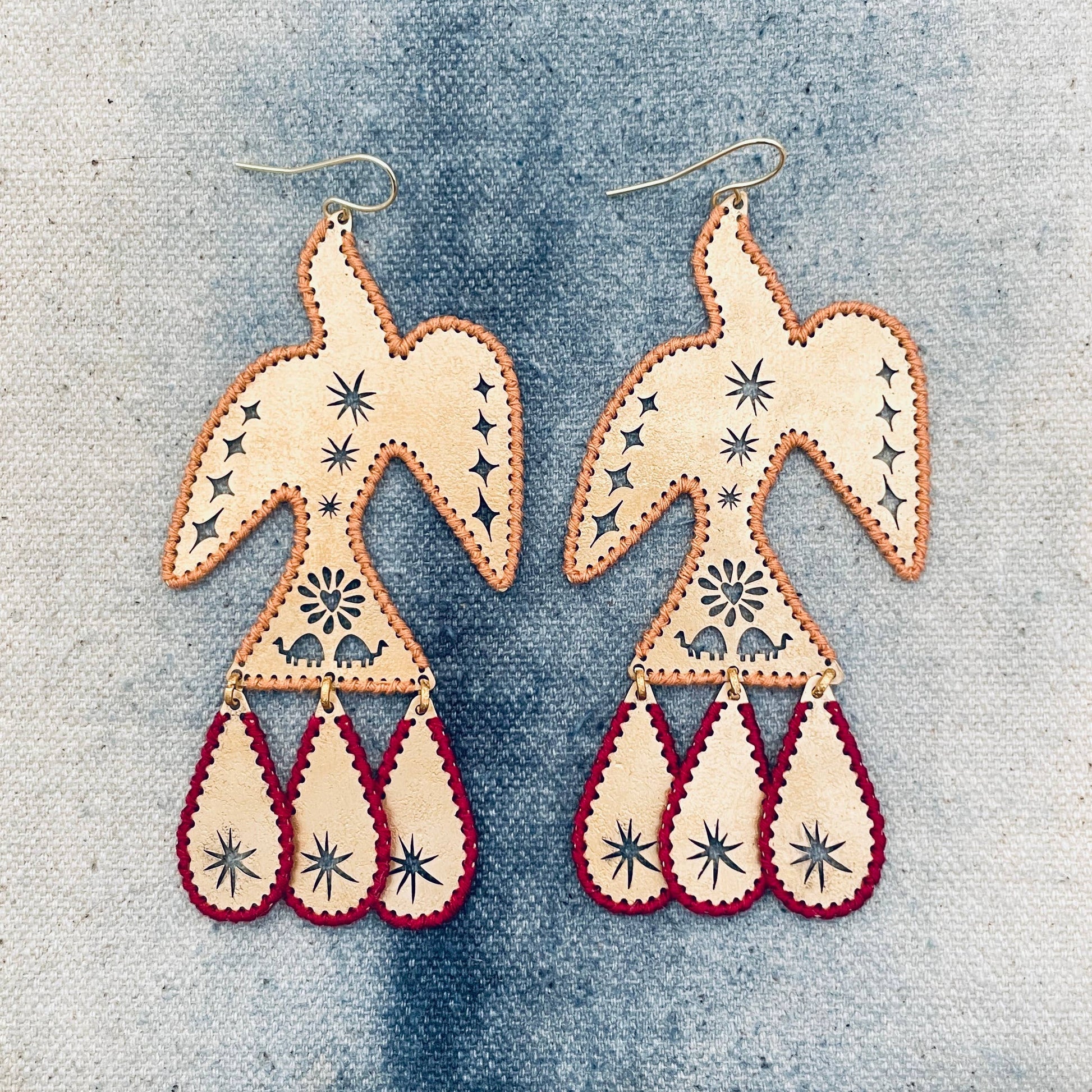 Pair of bird-shaped earrings with star patterns on a denim background