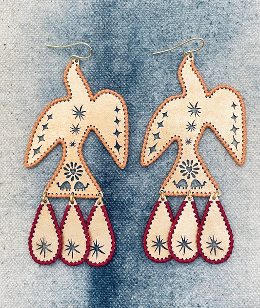 Pair of bird-shaped earrings with star patterns on a denim background