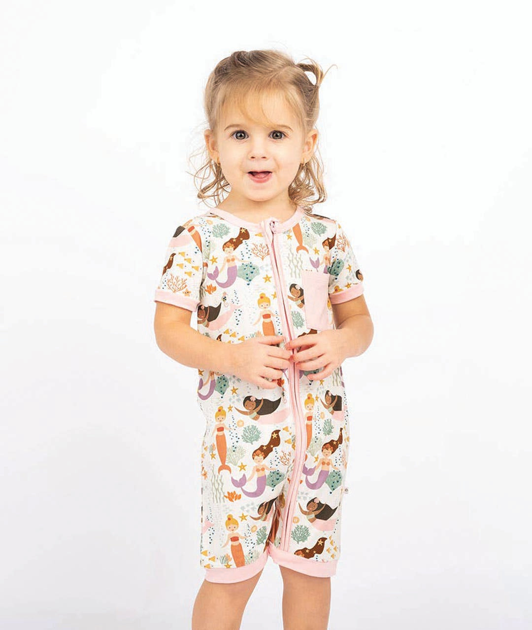 Child wearing a patterned onesie on a white background