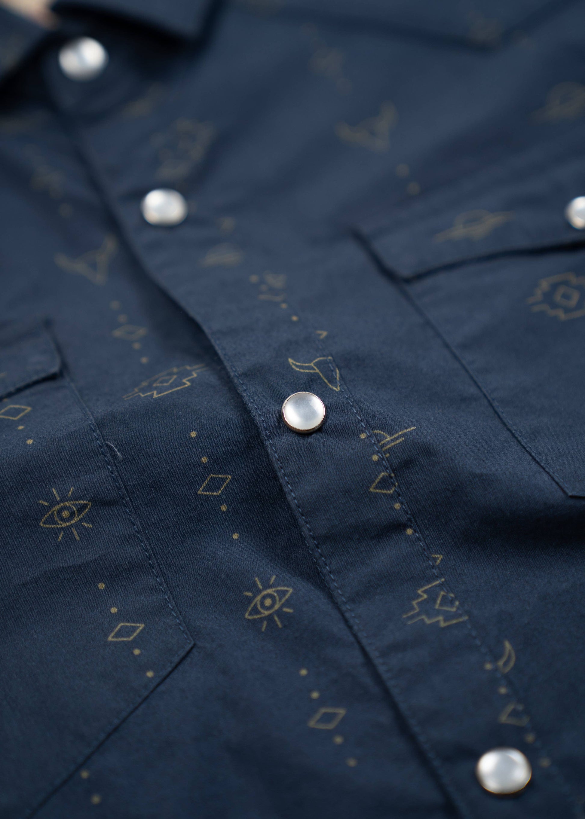 close up of pearl buttons on navy western shirt with small patterns